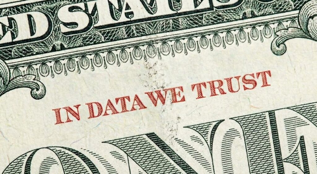 primer plano de un billete de dolar con la frase "in data we trust" escrita en rojo